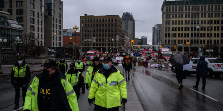 Police officers walk along a street during a protest by truck drivers over pandemic health rules and the Trudeau government, outside the parliament of Canada in Ottawa on February 17, 2022. (Photo by Ed JONES / AFP) هجمات في ساسكاتشوان الكندية تسفر عن سقوط قتلى وجرحى