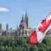 Canadian flag waving with Parliament Buildings hill and Library in the background شركات ترغب في تسريح عمالها الكنديين في 2023